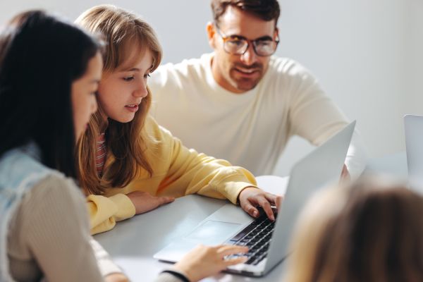 Profesor apadrina a dos jóvenes mujeres a enseñarles el uso de la tecnología, computadores para mejorar sus oportunidades futuras en educación o trabajo.