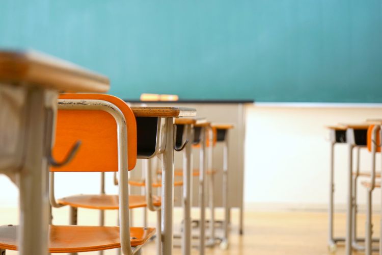 Aula vacía con pupitres y pizarra representa el entorno de los centros educativos donde se desarrollan programas de formación y aprendizaje escolar.