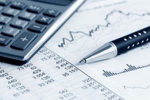 Bolígrafo y calculadora sobre un documento con gráficos que representan la contabilidad en una Fundación sin ánimo de lucro.