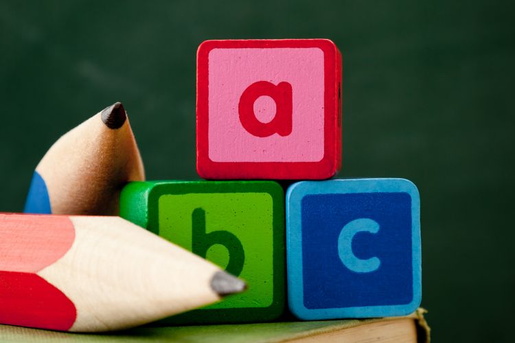 Bloques educativos con letras y lápices de colores representan los contenidos formativos básicos en la etapa inicial del aprendizaje infantil y escolar.