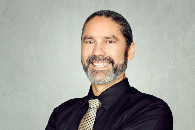 Ejecutivo sonriente con camisa negra y corbata clara
